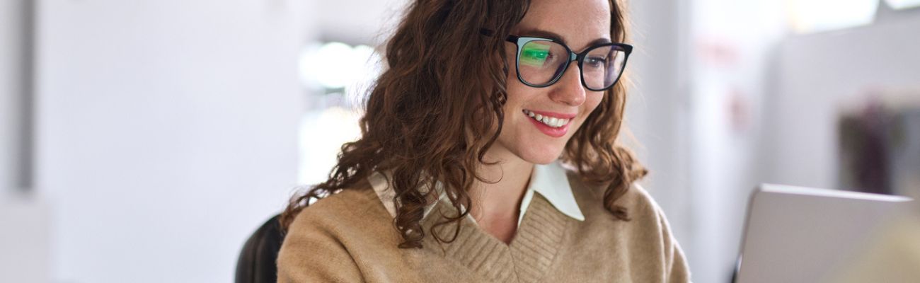 Frau mit Locken und Brille vor Laptop