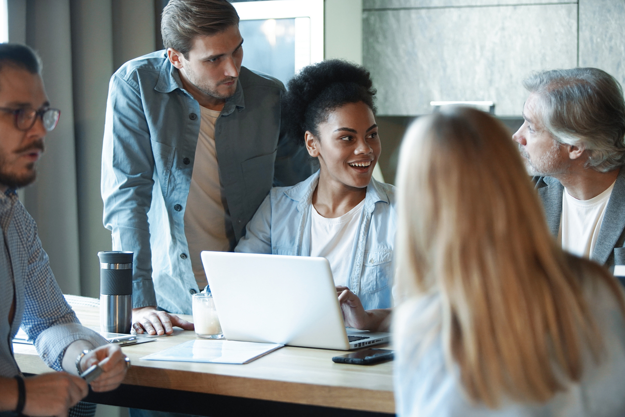 verschiedene Businessleute, welche um einen Laptop stehen