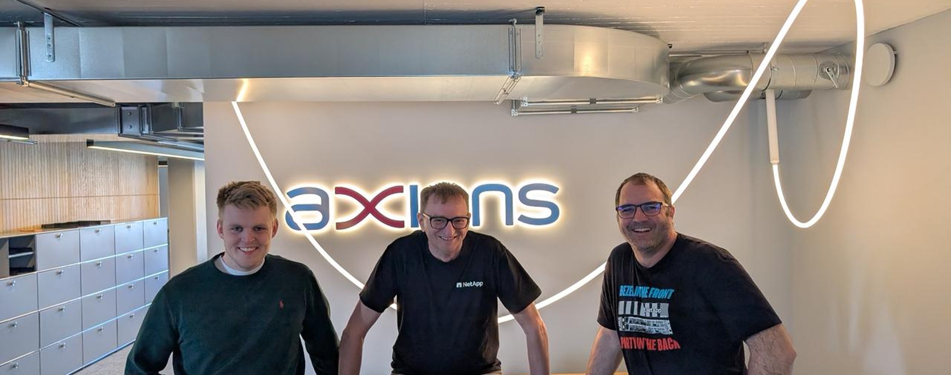 Tre uomini davanti al logo di Axians