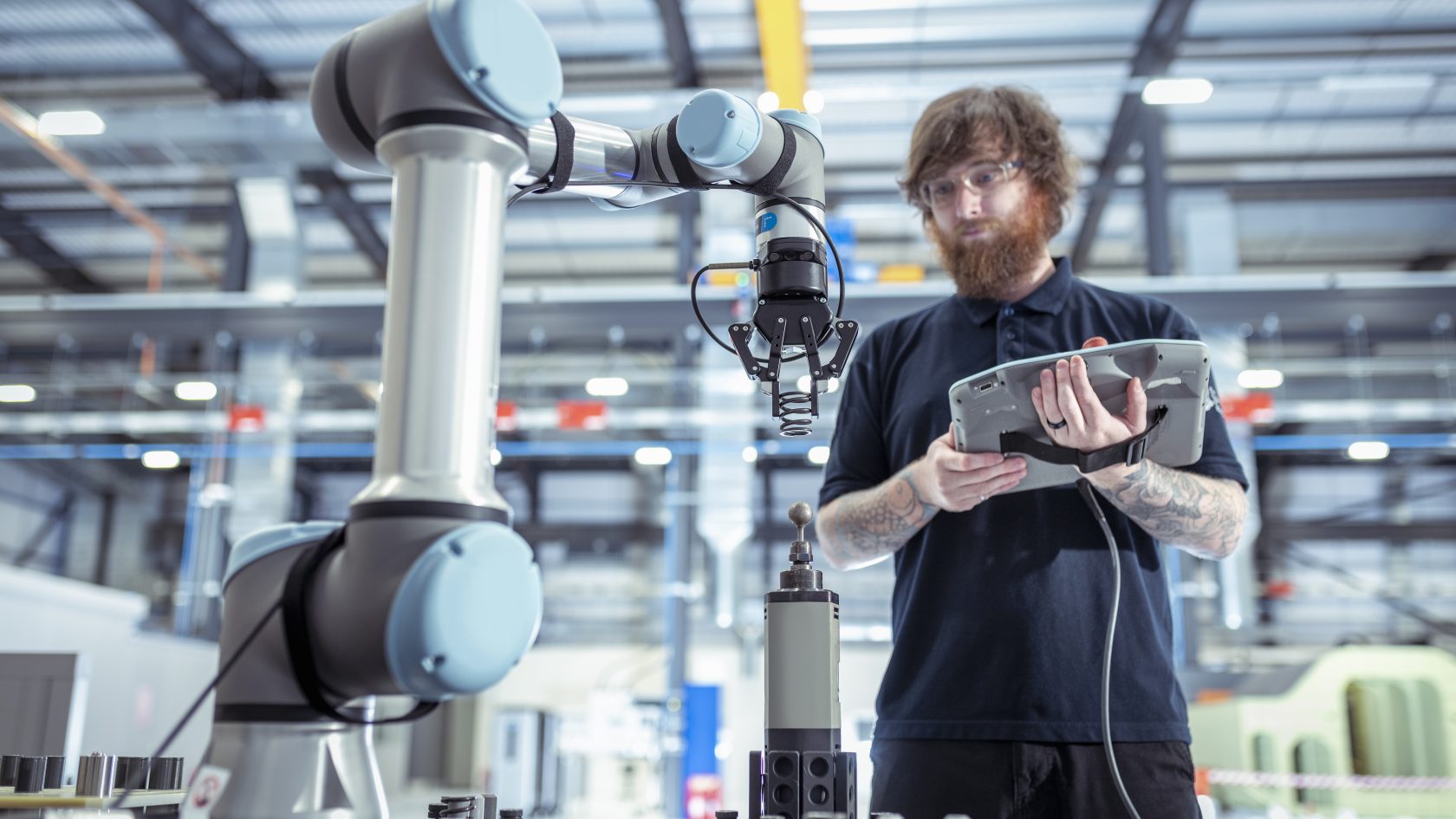 Bild einer Mannes in einer Werkstatt mit Tablett und Roboterarm