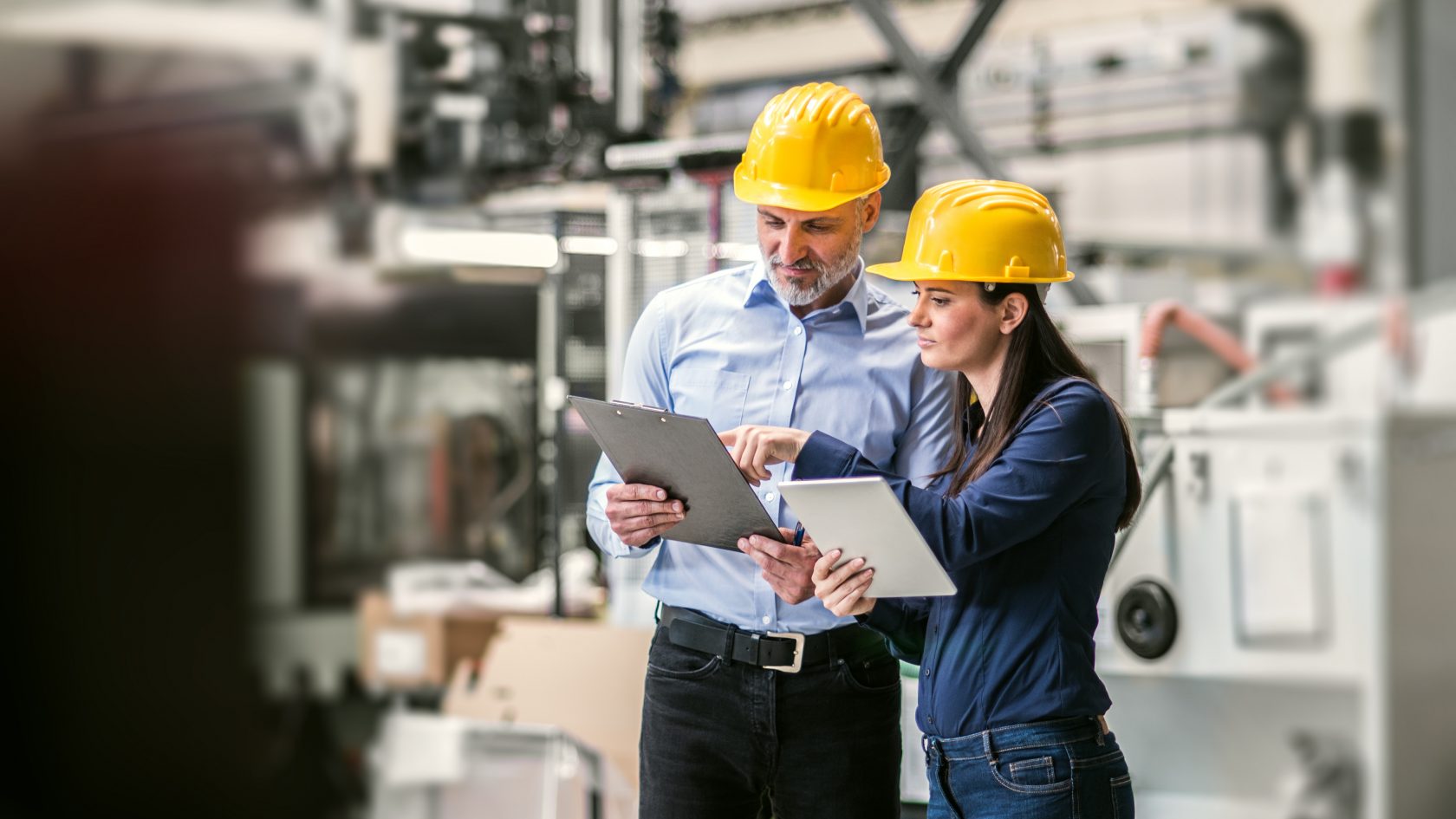 Bild 2 Personen in einer Werkstatt mit Helm und Tabletts