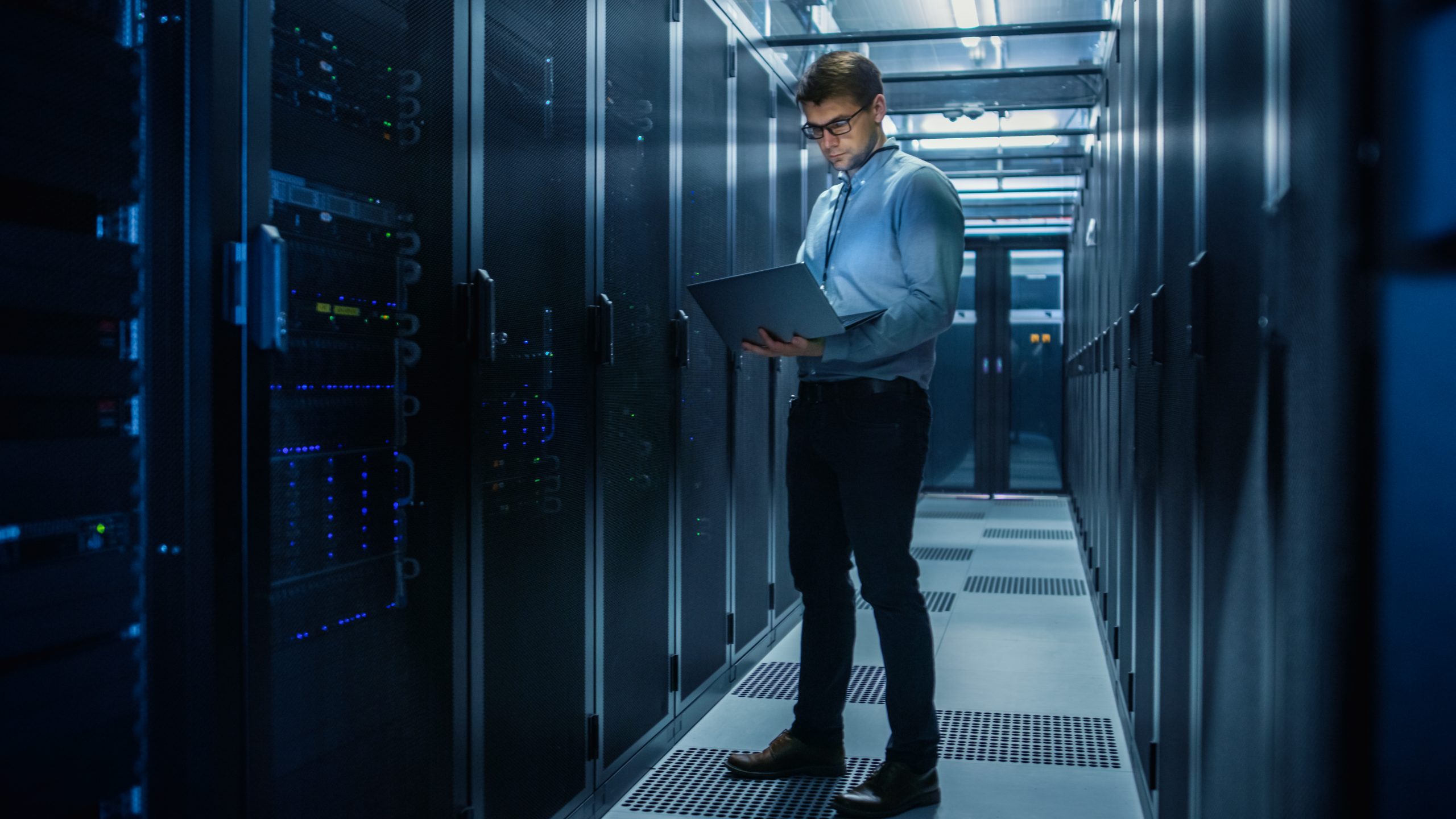 Mitarbeitender von Axians mit Laptop im Serverraum